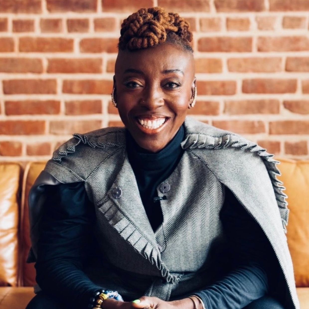 Smiling person with unique hairstyle and stylish outfit.