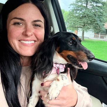 Woman smiling with her dog in a car.