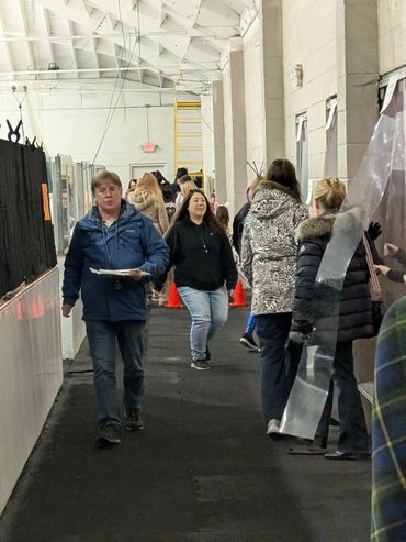 People walking inside a large indoor space, some holding items.