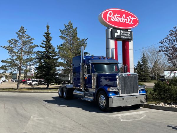 Blue Peterbilt truck parked outside dealership.
