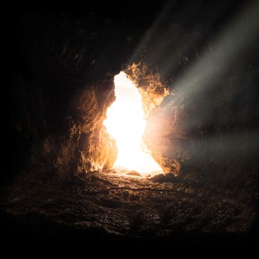 Sunlight streaming through the opening of a dark cave
