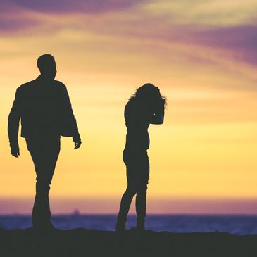 Silhouettes of a man and woman at sunset by the sea