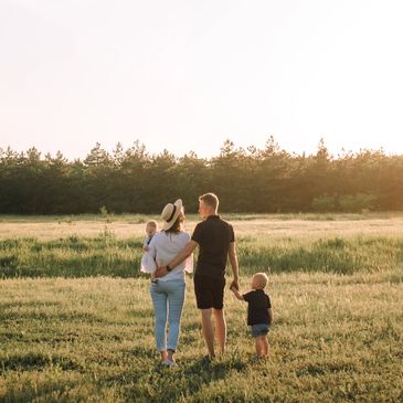 Family walking in a sunlit meadow during sunset