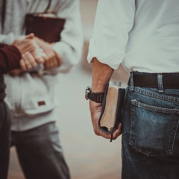 Person holding a Bible with others shaking hands in the background