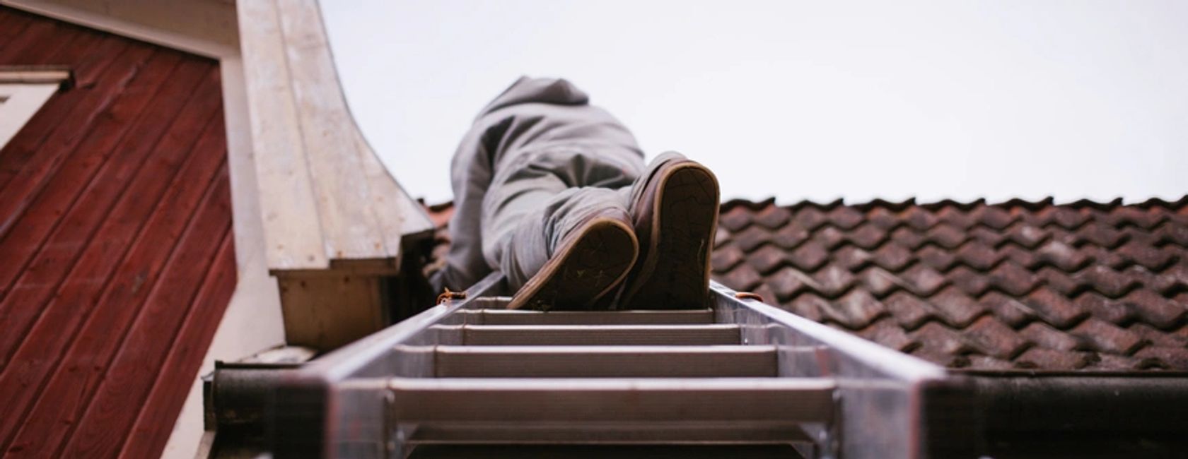 Roof repair being carried out by a roof tiler on a ladder