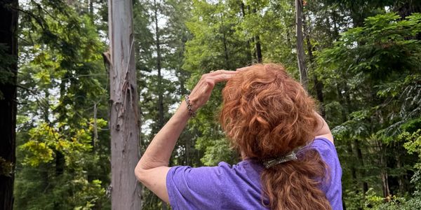 Woman with red hair observing nature in a forest.