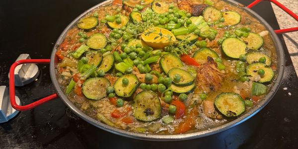 A large pan filled with vegetable paella cooking.