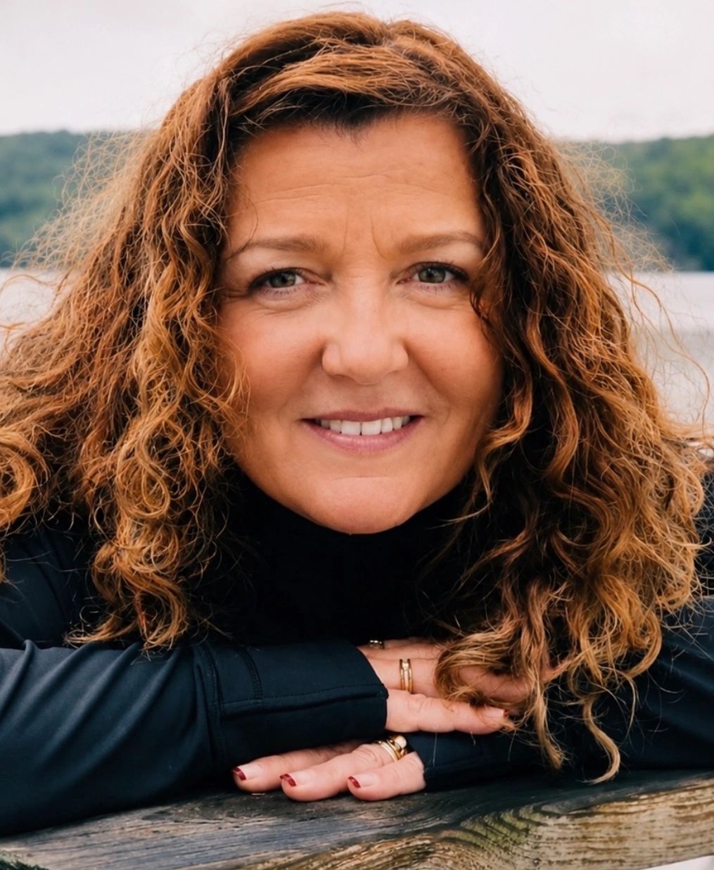 Woman with curly hair smiling outdoors.