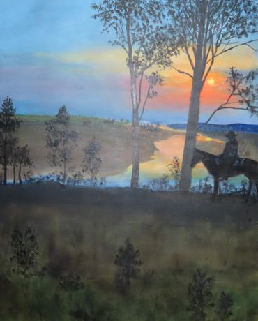 Silhouette of a rider on horseback at sunset near a river.