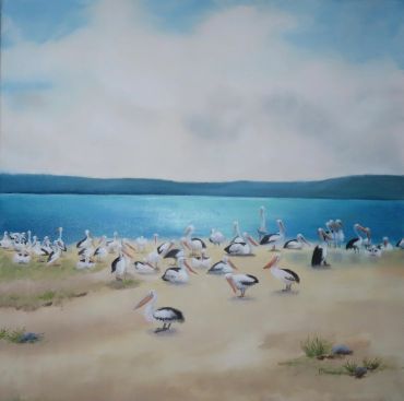 Pelicans gathered by a calm lakeside on a cloudy day.