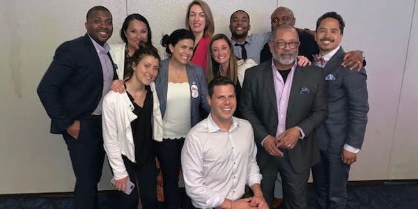 A group of ten diverse professionals posing together in formal attire.