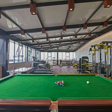 Indoor recreational room with pool table, gym equipment, and air hockey table.