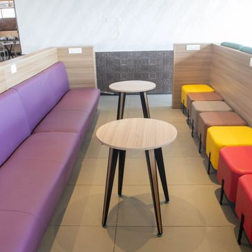 Modern lounge with colorful seating and wooden tables.