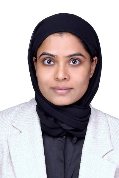 Portrait of a woman wearing a black hijab and light-colored blazer.