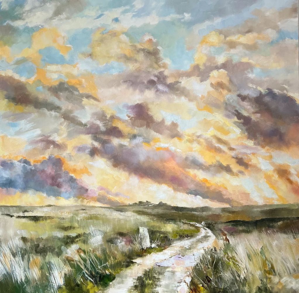 Dramatic landscape of clouds lit by setting sun against a pale blue sky rising above Lundy Island