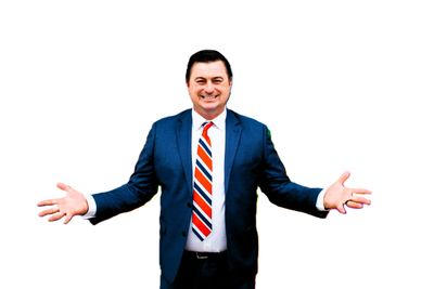 Man in suit with open arms and a welcoming smile.