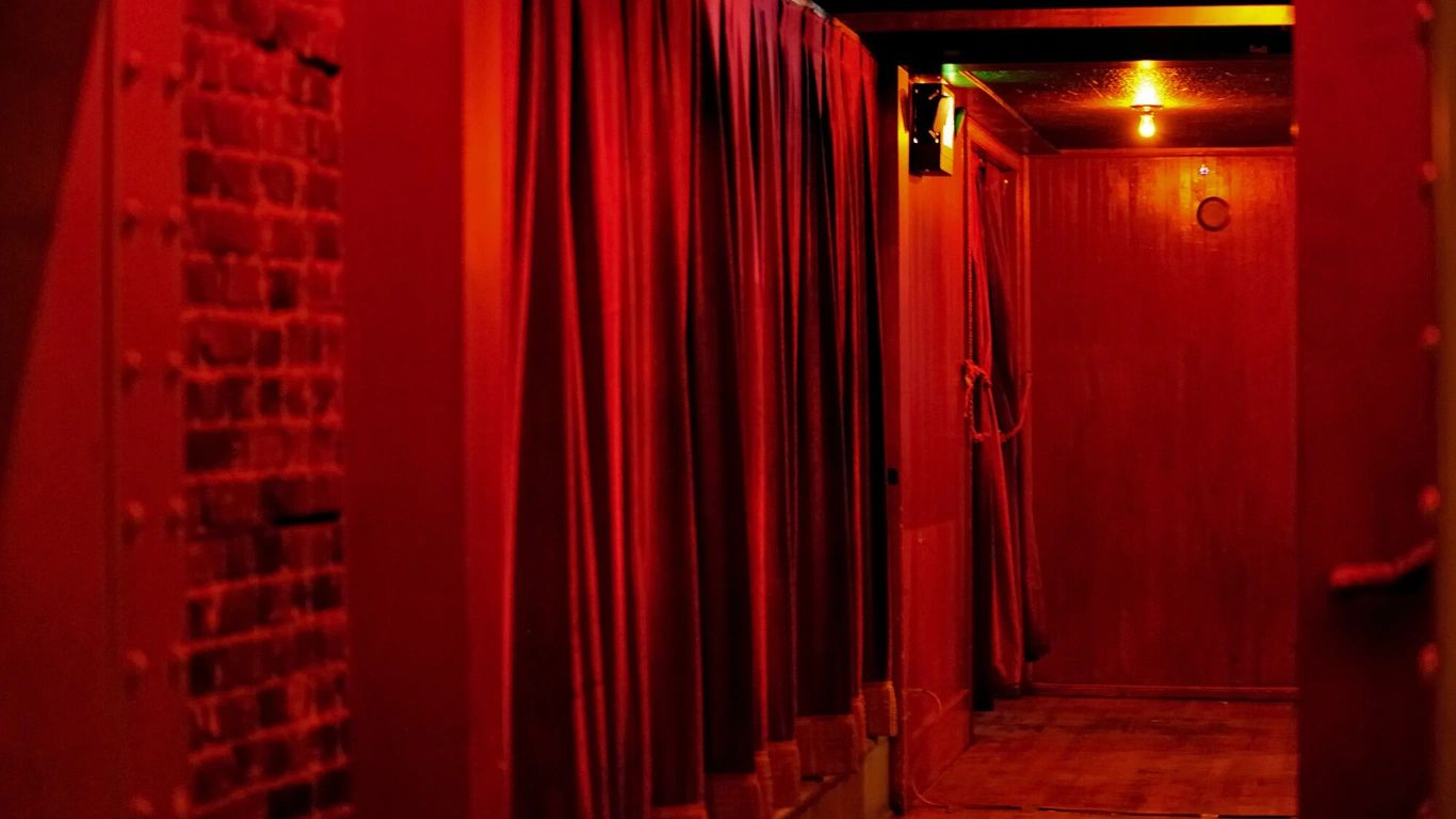 Dimly lit red hallway with curtains and door.