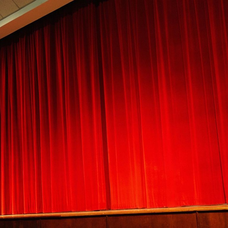 Closed red theater curtains on stage.