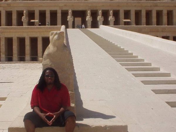 Man sitting by ancient Egyptian temple steps.