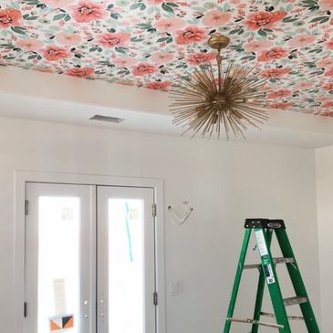 Room with floral ceiling and green ladder in front of double doors.