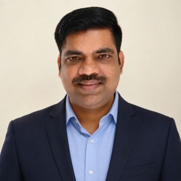 Professional headshot of a man in a suit and blue shirt.