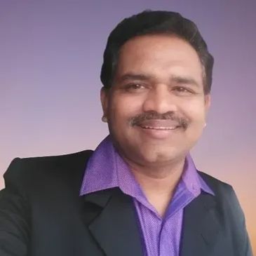 Smiling man in purple shirt and black jacket.