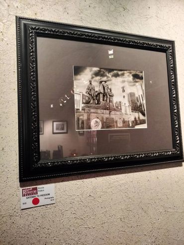 Framed black and white photo of a historic statue in an art gallery.