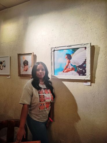 Woman posing beside colorful framed paintings on a textured wall.