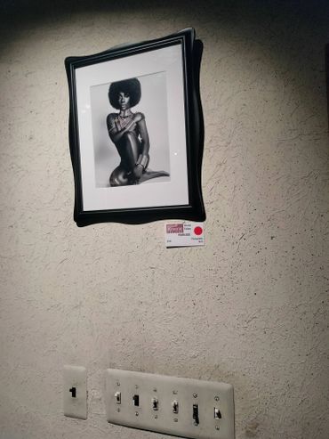 Framed black-and-white photo of a woman on a textured wall above light switches.