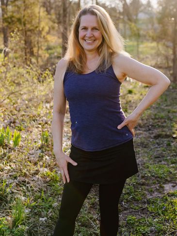 Woman smiling outdoors in casual workout clothes.