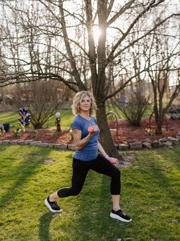 Woman exercising with dumbbells in a park.