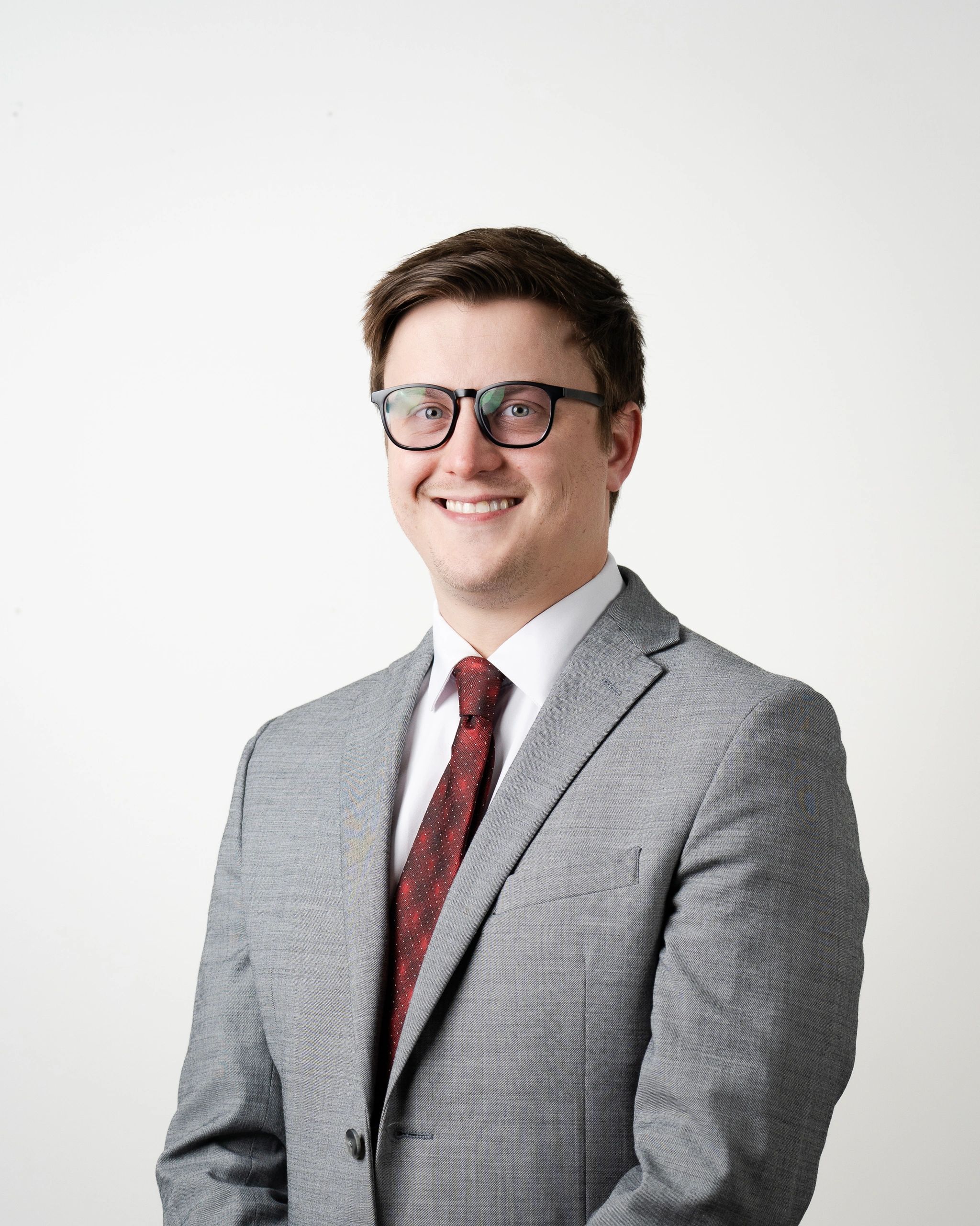 Man in a gray suit and red tie smiling confidently.