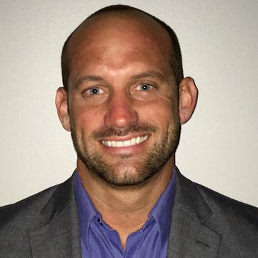 Smiling man in a suit jacket and blue shirt.