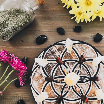 Crystal grid, pink and yellow flowers, herbs in glass jar with cork, crystals, wood table