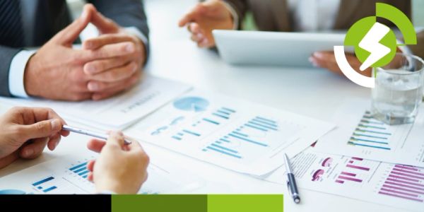 Business meeting with hands, charts, and documents on a table.