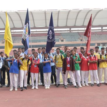Group of students holding colorful flags at a sports stadium.