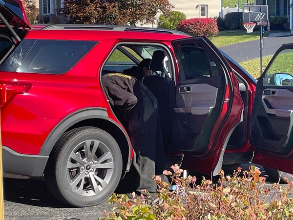 Person leaning into the backseat of a red SUV with open doors.