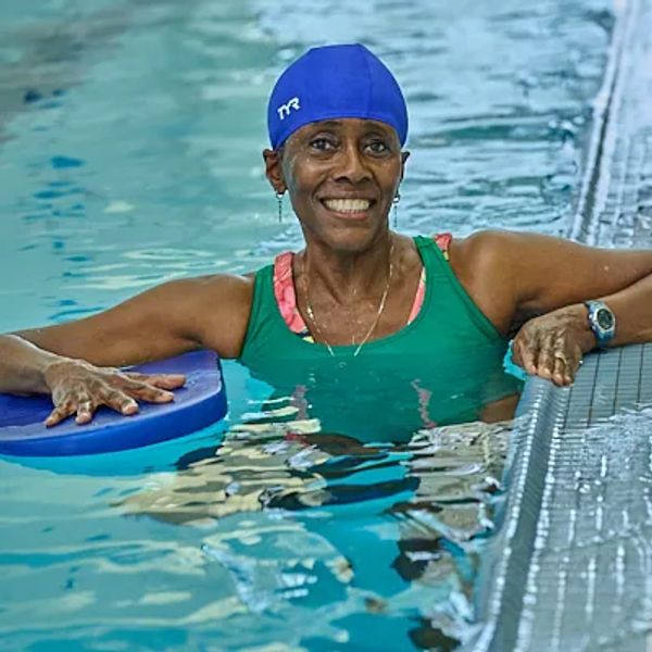Smiling woman in a swimming pool with swim cap.