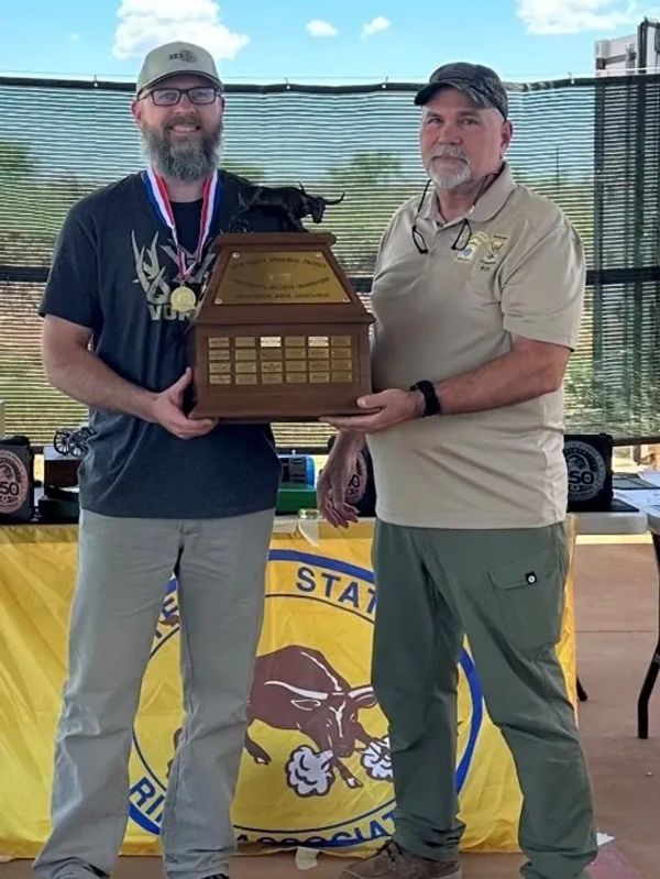 Two men holding a trophy with a bull figure.