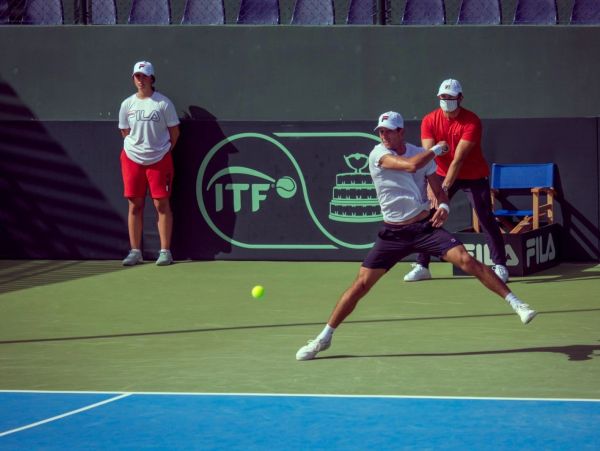 Tennis player executing a backhand shot during a match.