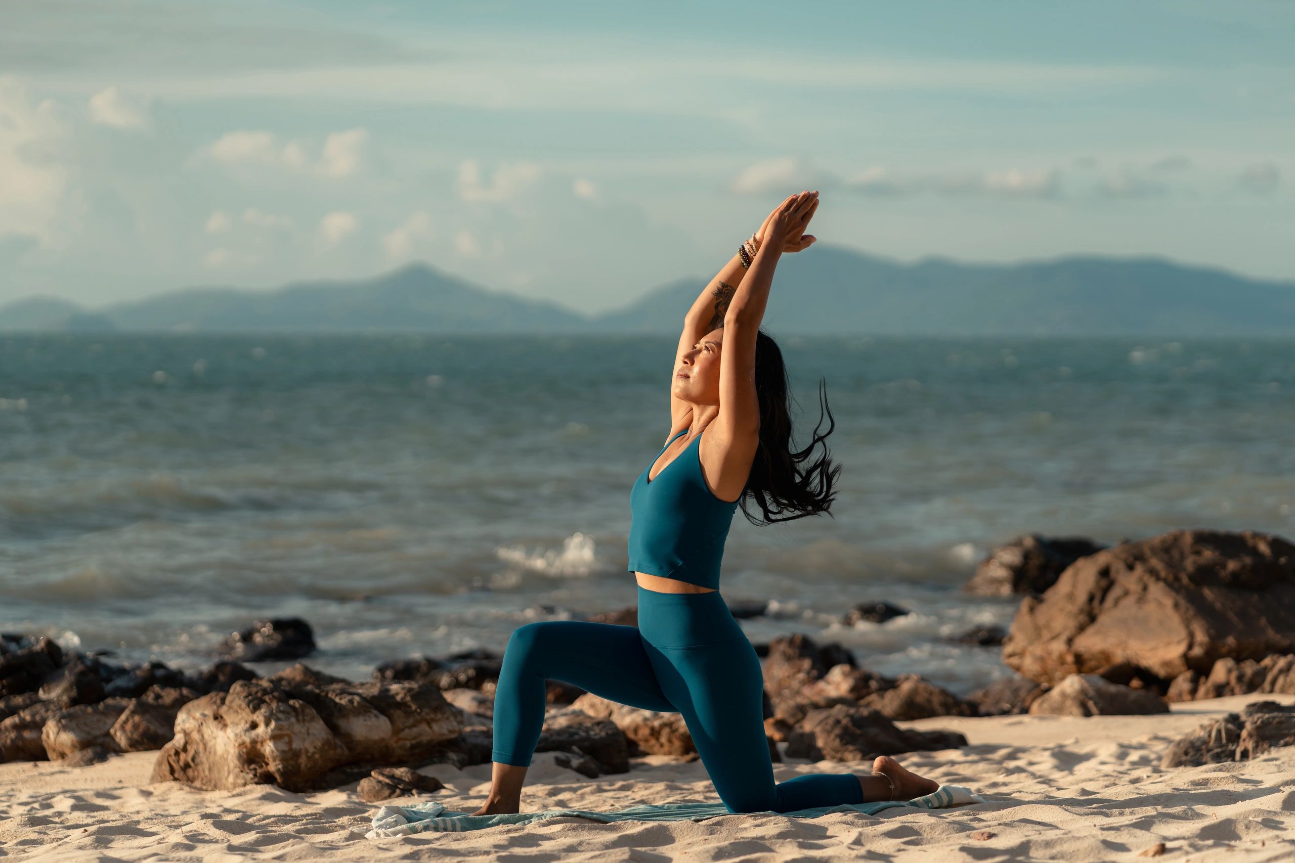 Woman practicing yoga on the beach at sunrise.