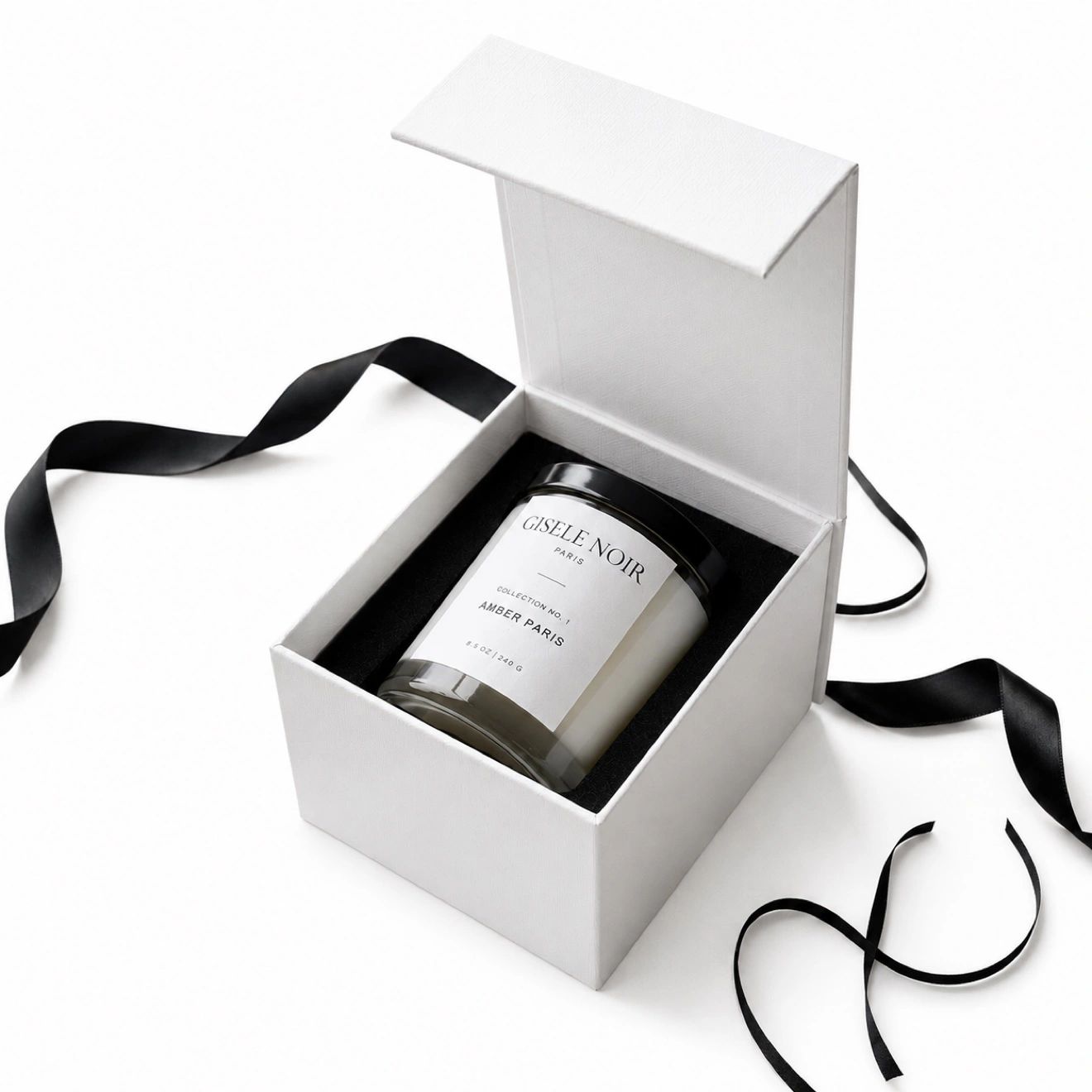 White gift box with black ribbon containing an Amber Paris candle.
