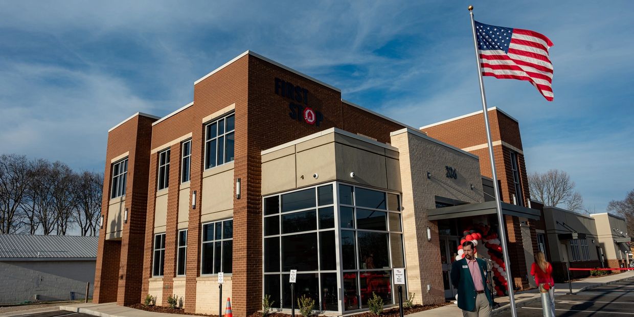 Modern brick and glass building with American flag and people outside.