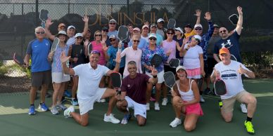 Group photo of pickleball players on a court, posing happily.