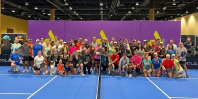 Large group photo on indoor tennis court.