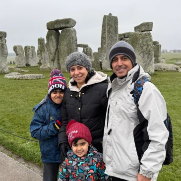 Family posing at Stonehenge on a cloudy day.