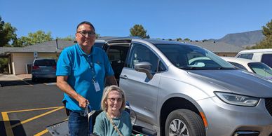 Driver poses near his van with a woman in a wheelchair.