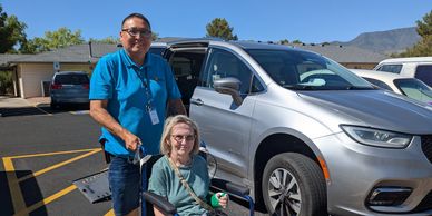 Driver poses near his van with a woman in a wheelchair.