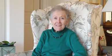Mary, once a volunteer and now a client sitting in a chair in her home.