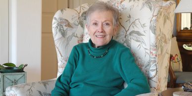 Mary, once a volunteer and now a client sitting in a chair in her home.